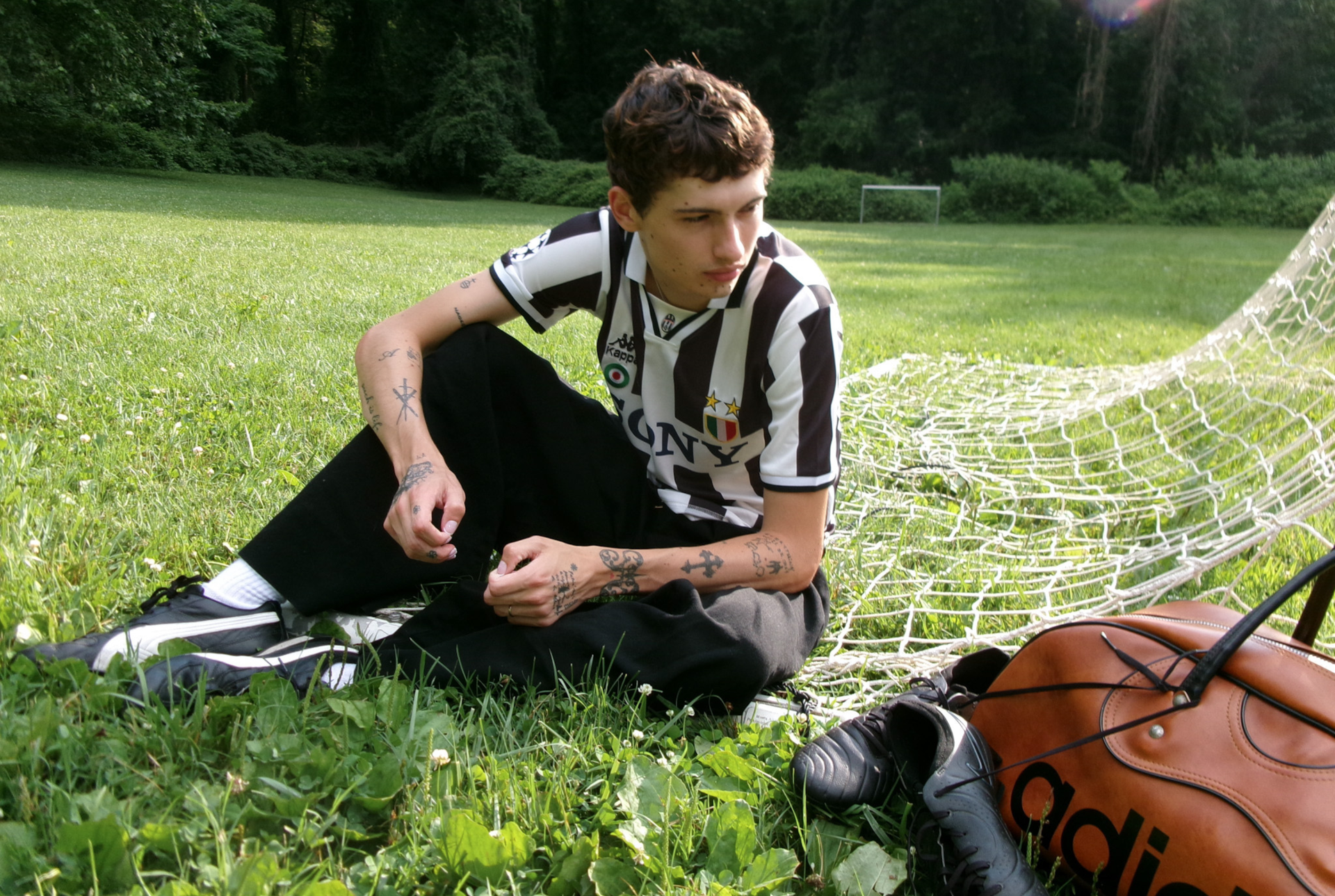 Musician Glaive sitting on a football pitch beside goals.