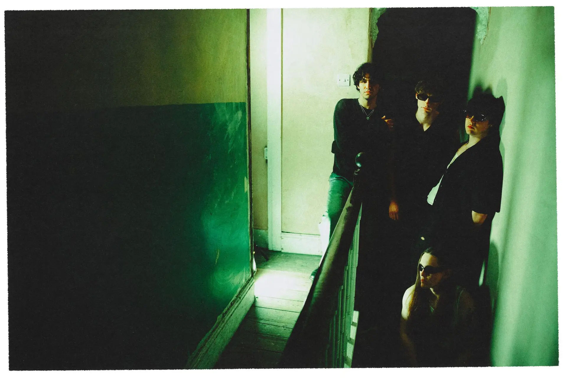 3 men standing in a dark corridor with green lighting