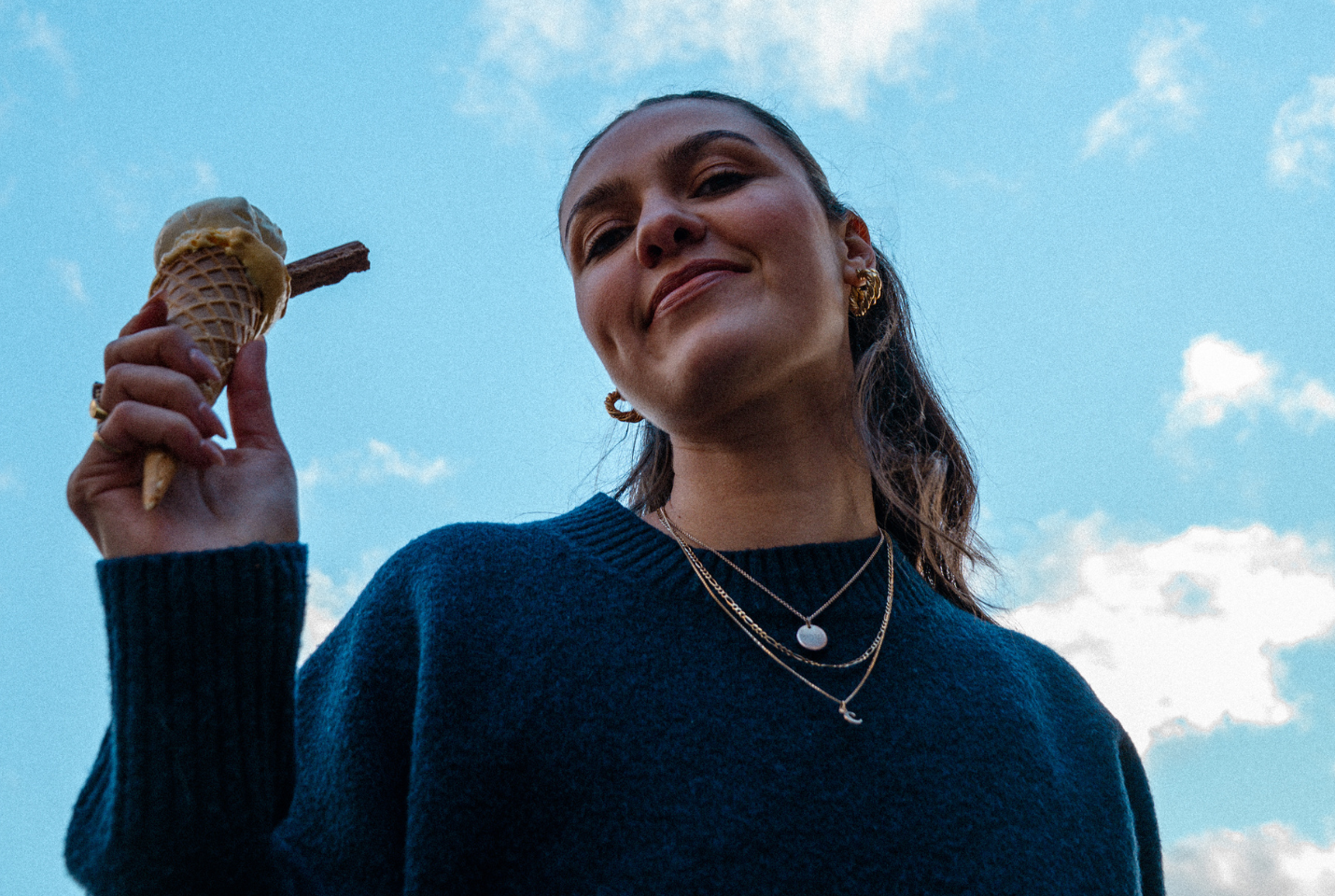 girl holding an ice cream cone with blue sky behind