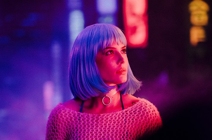 Halsey met een felblauwe pruik en een doorzichtige gebreide top, gefotografeerd in paarsroze neonlicht met vage lichtreclames op de achtergrond