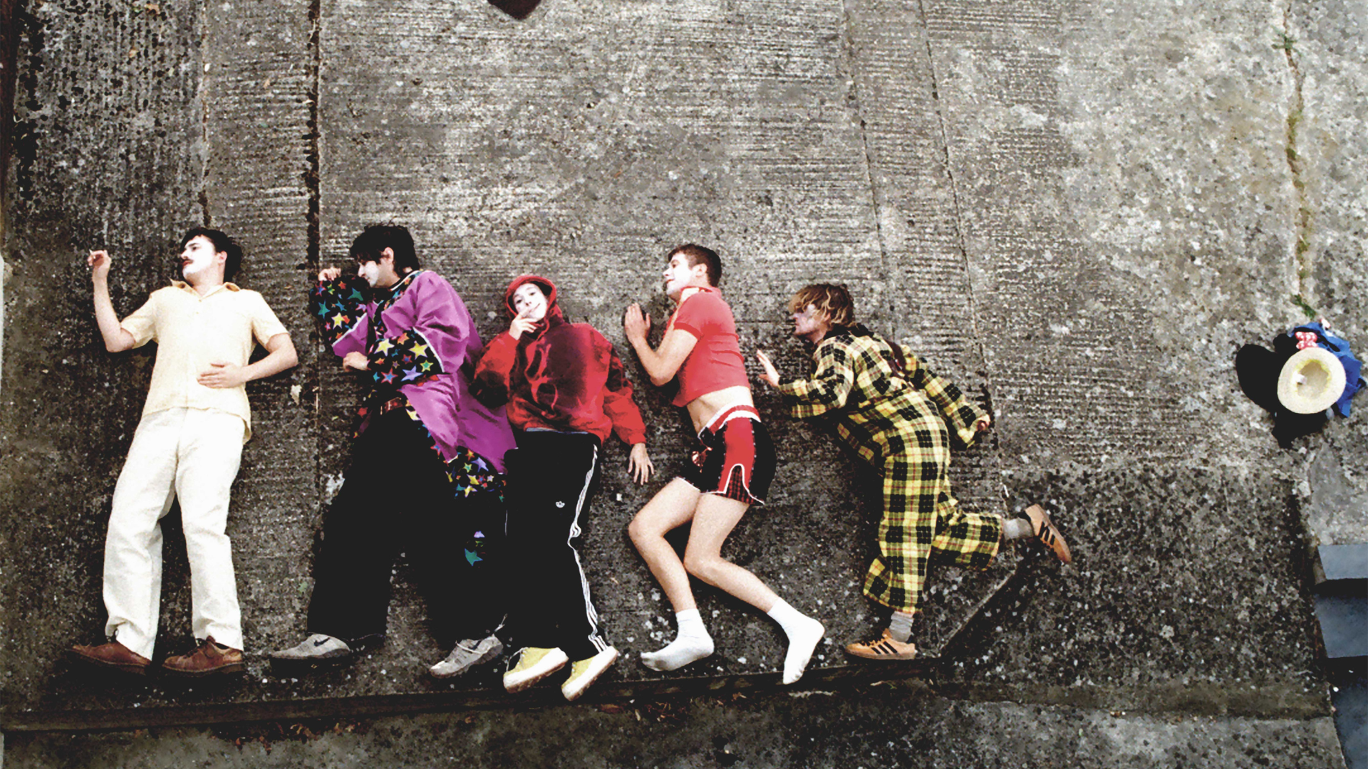 Members of the band 'Sorry' lying on a concrete floor.