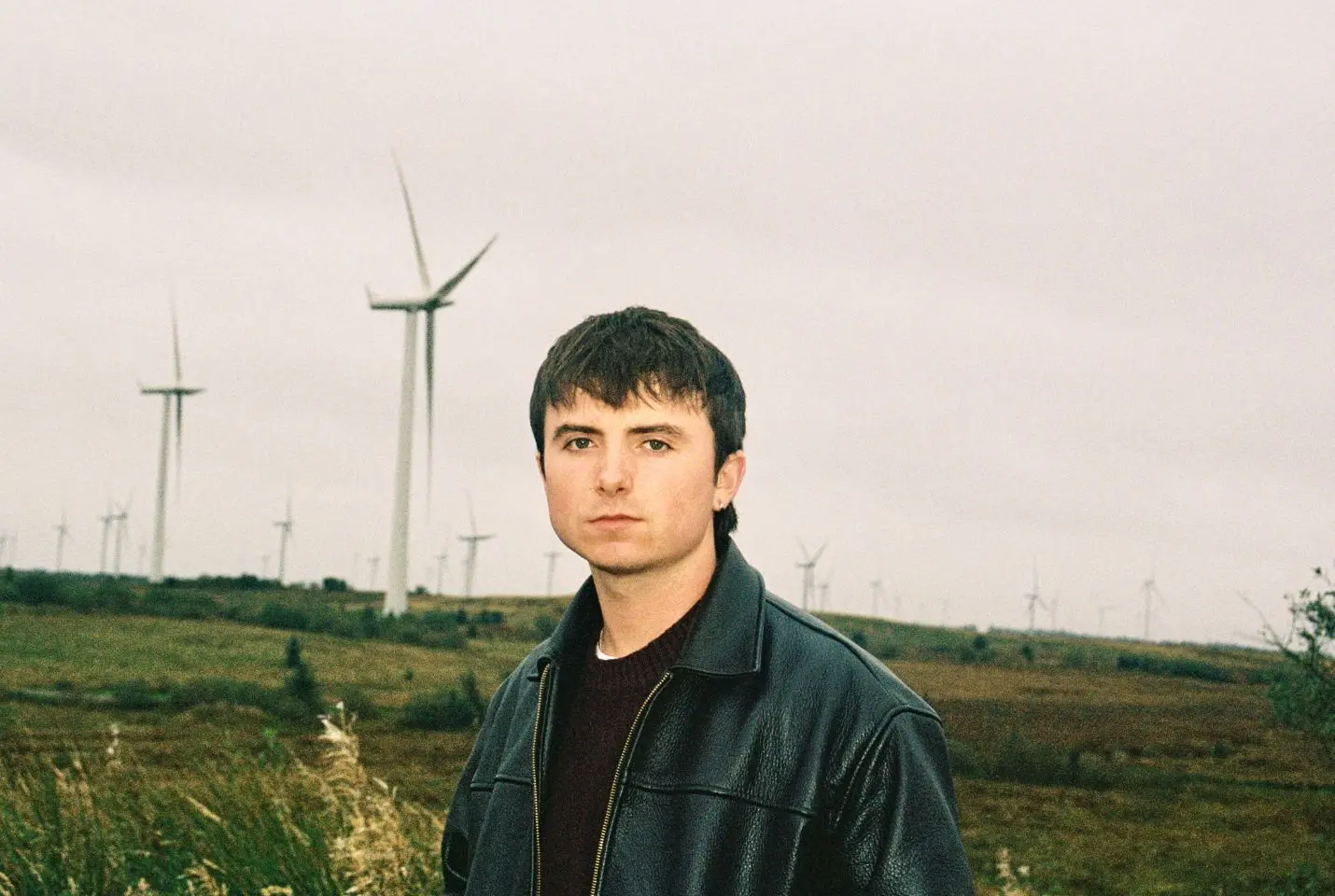 A man in a leather jacket stood in a filed
