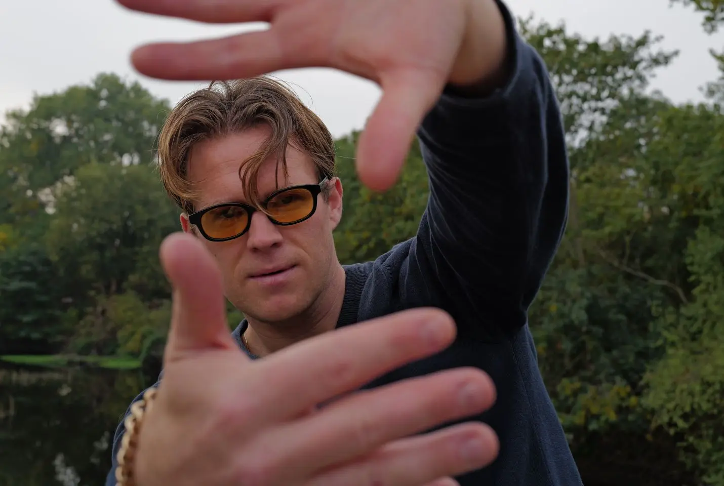 A man wearing orange lensed glasses and a blue jumper