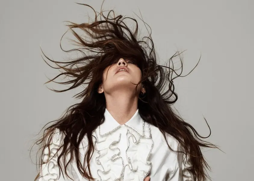 Joan As Police Woman with her head leaned back and hair flying in the air