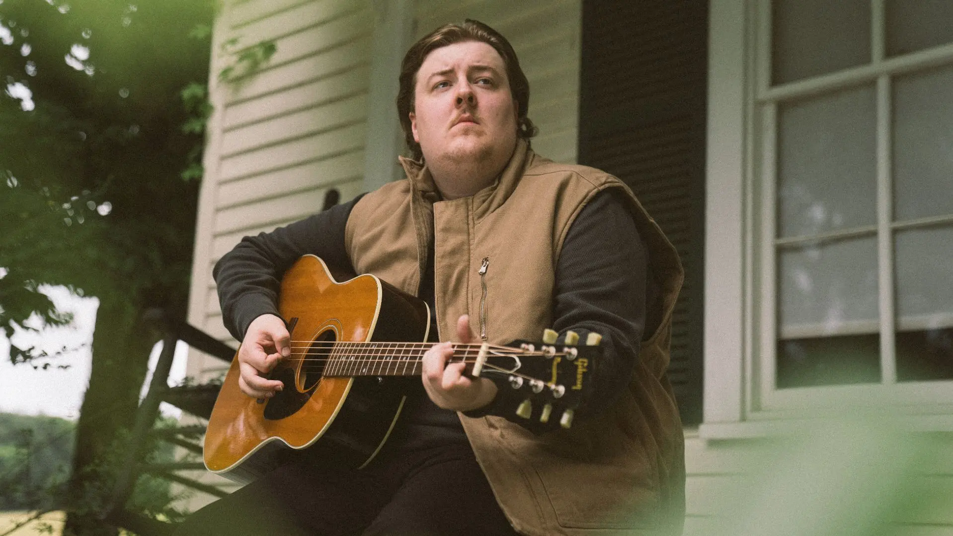 Gareth sat on a porch holding a guitar