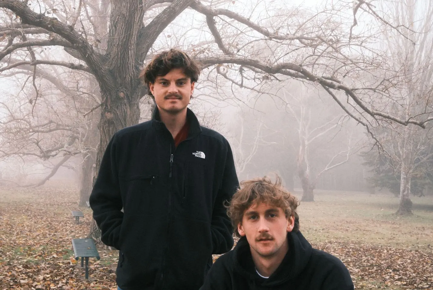 2 men posing in front of a tree in autumn