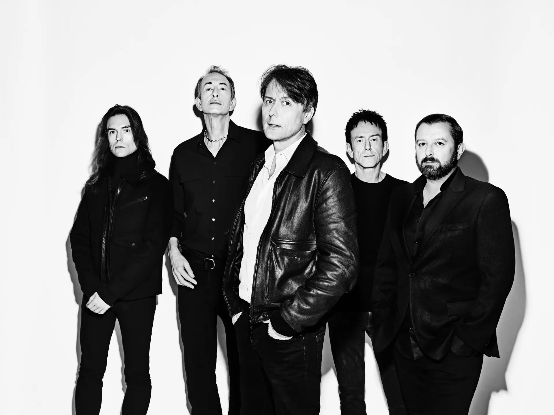 group of 5 men standing against white background. picture in black and white