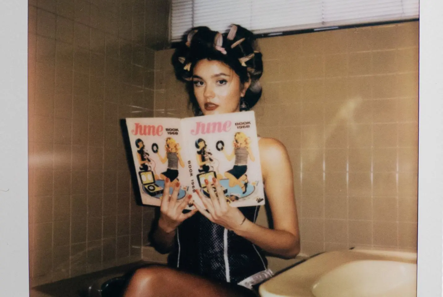 Ruby Roberts holding a magazine with rollers in her hair