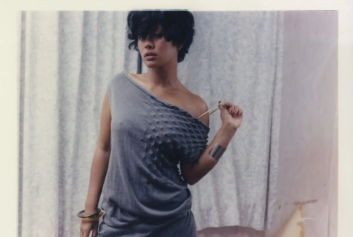 A woman with short dark hair wearing a grey knitted dress