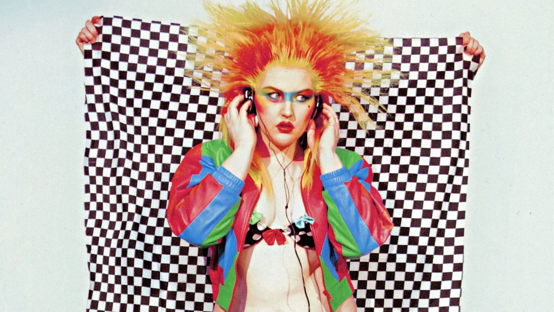 Caroline Kingsbury with bright orange spiky hair and a multi coloured jacket