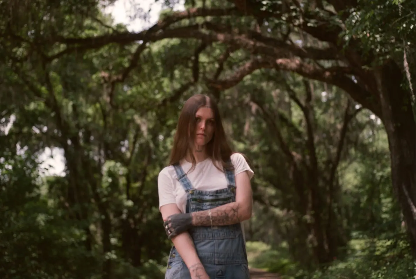 Ethel Cain stood in a white tshirt and blue overalls