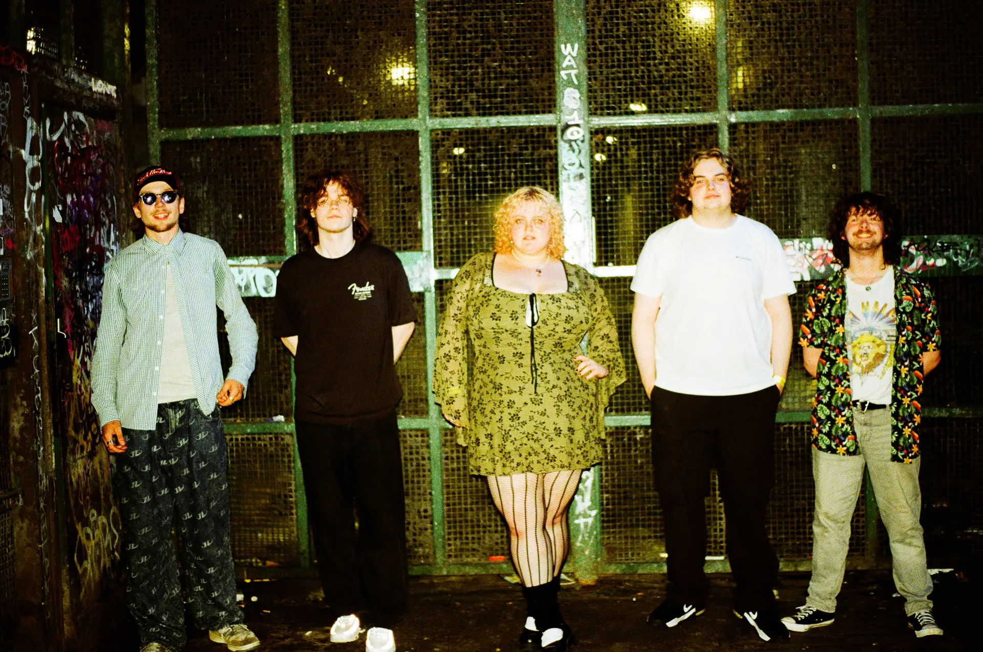 5 band members posing in front of a window pane