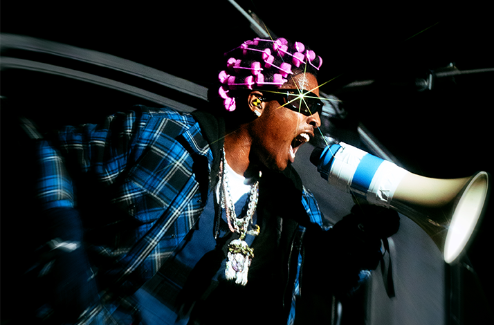ASAP Rocky draagt een zonnebril, blauw ruitjeshemd en schreeuwt door een megafoon