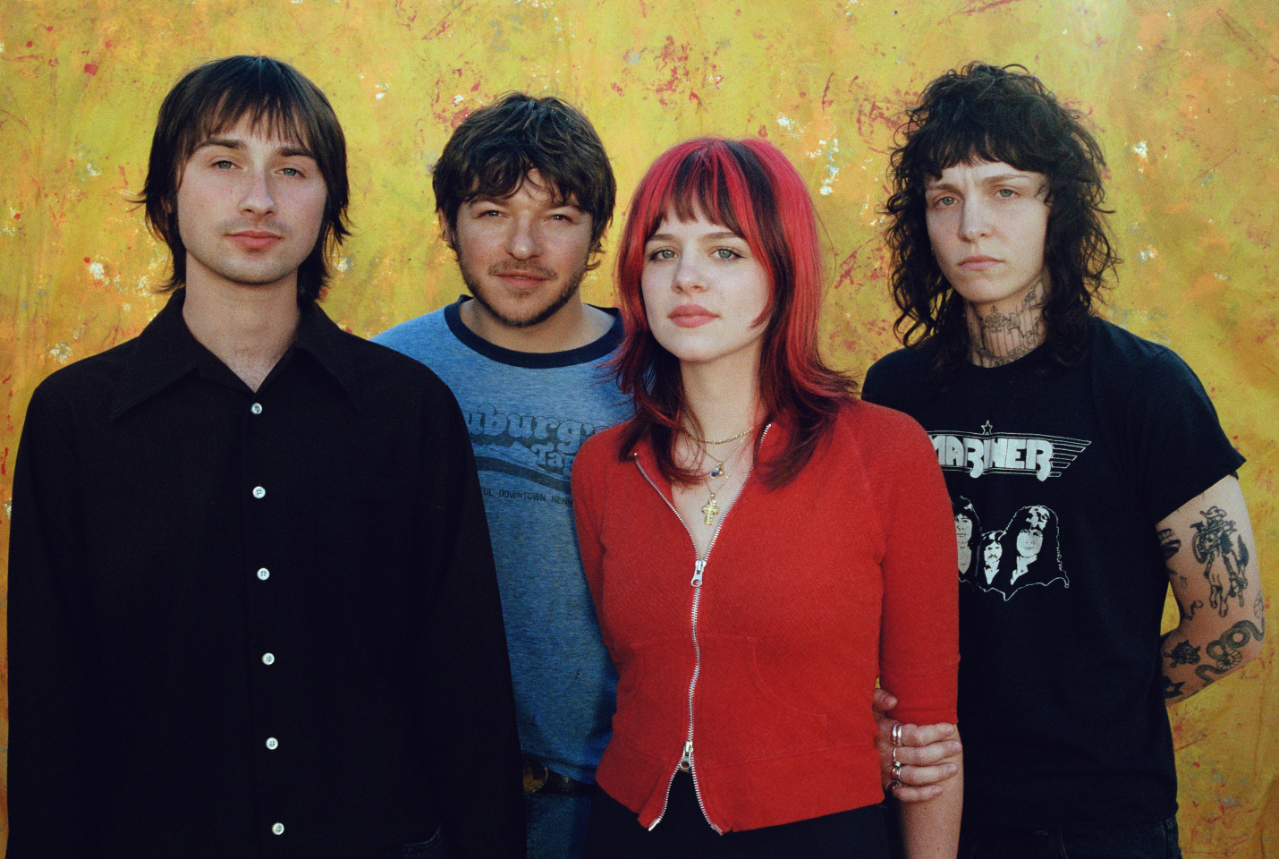 a group of four people in front of a yellow wall