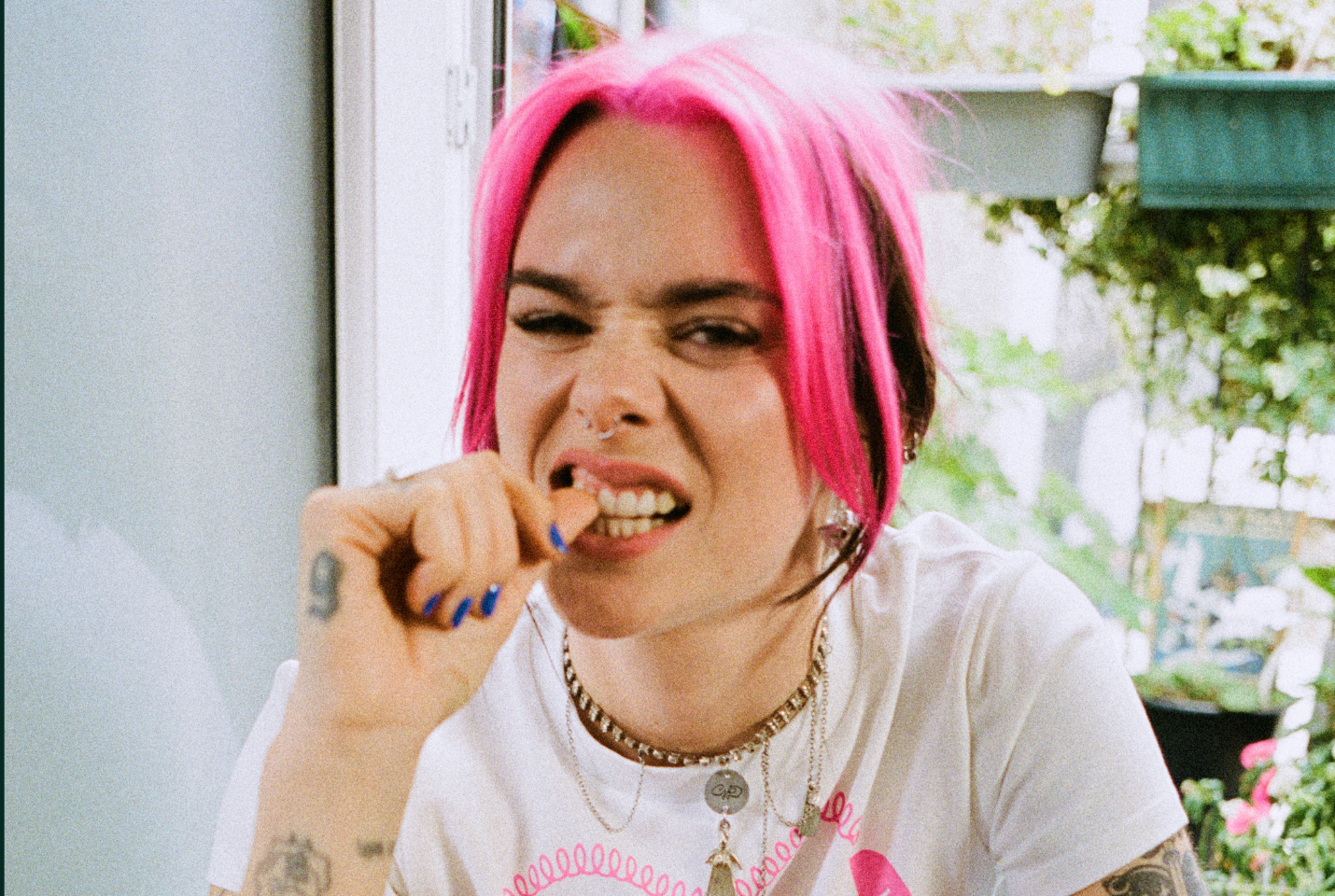Garli biting her thumb with pink hair