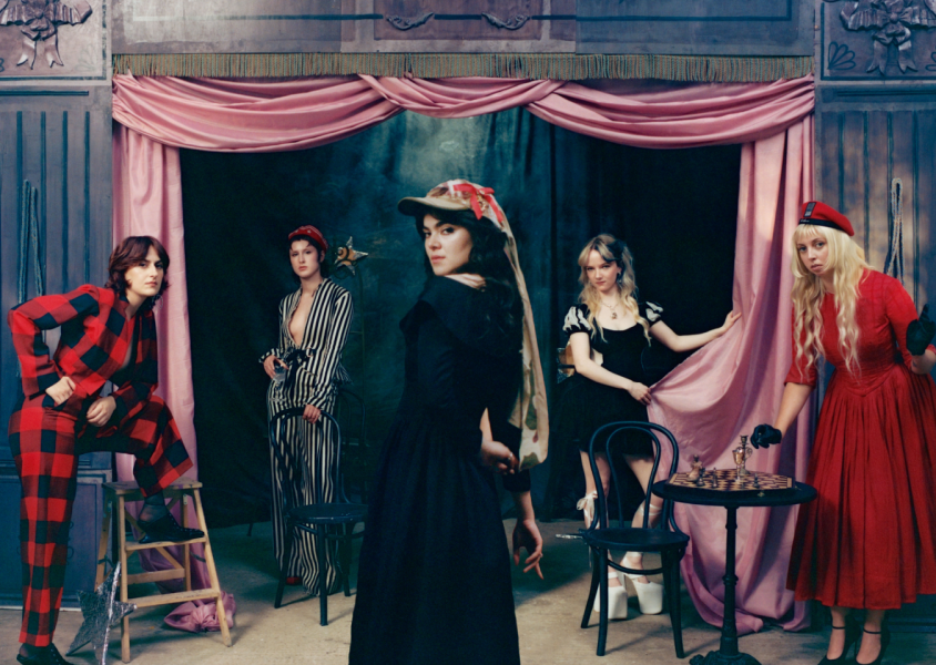 Five people in a room draped in pink curtain