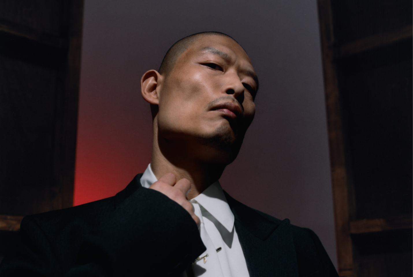 close up of man in white shirt and blazer standing in front of dark background