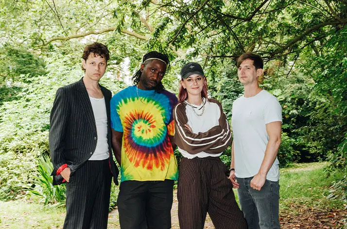 De vier leden van Bloc Party staan naast elkaar op de foto met groene bomen op de achtergrond
