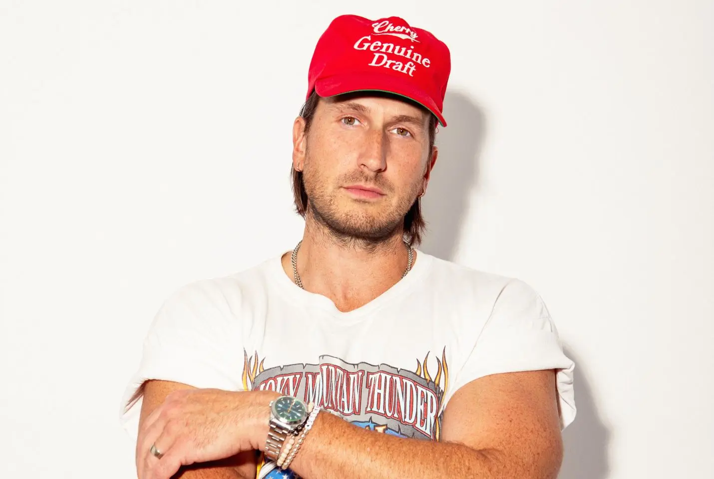 Russell Dickerson in a white graphic tee and red cap