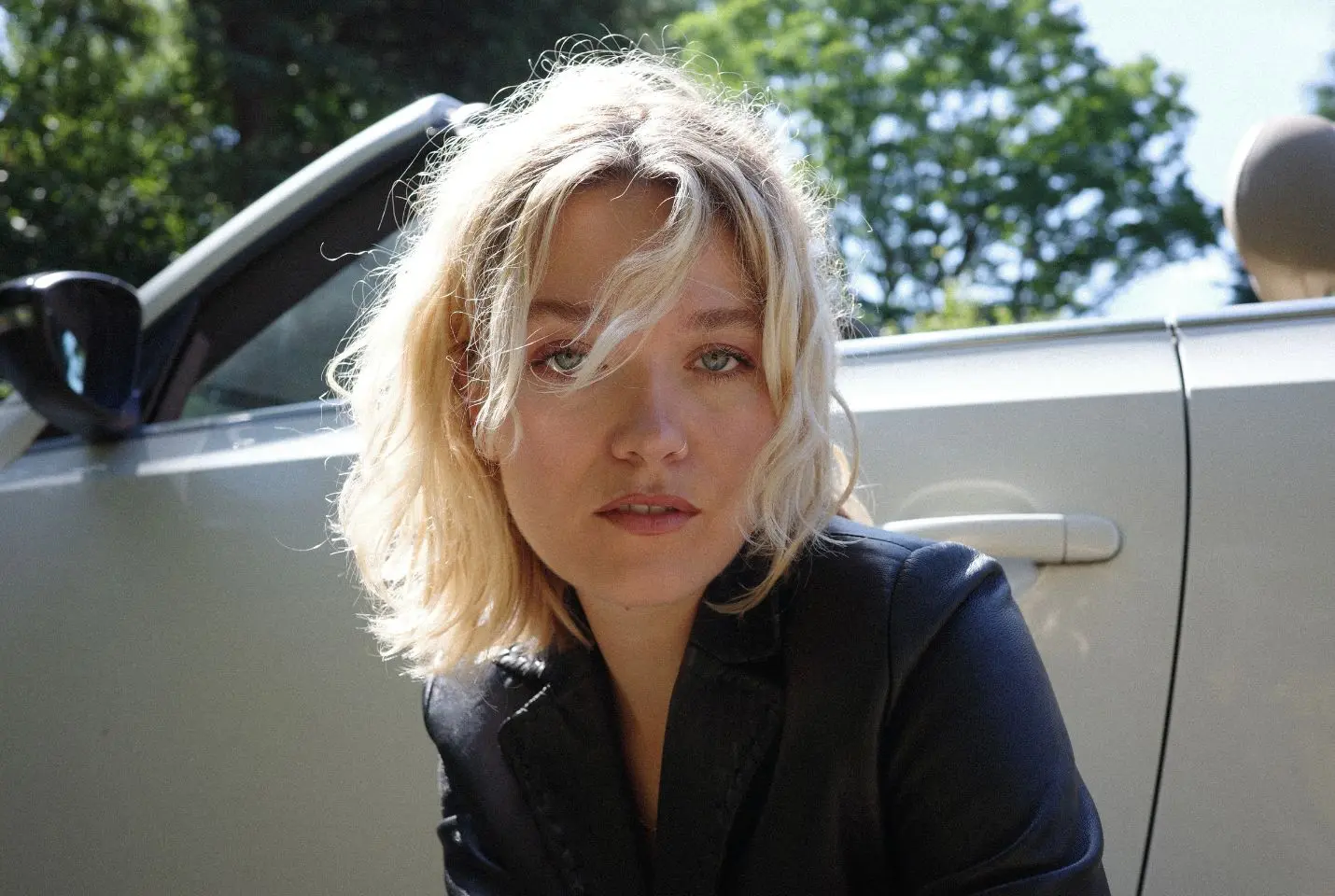 girl with blonde hair in front of silver convertible car