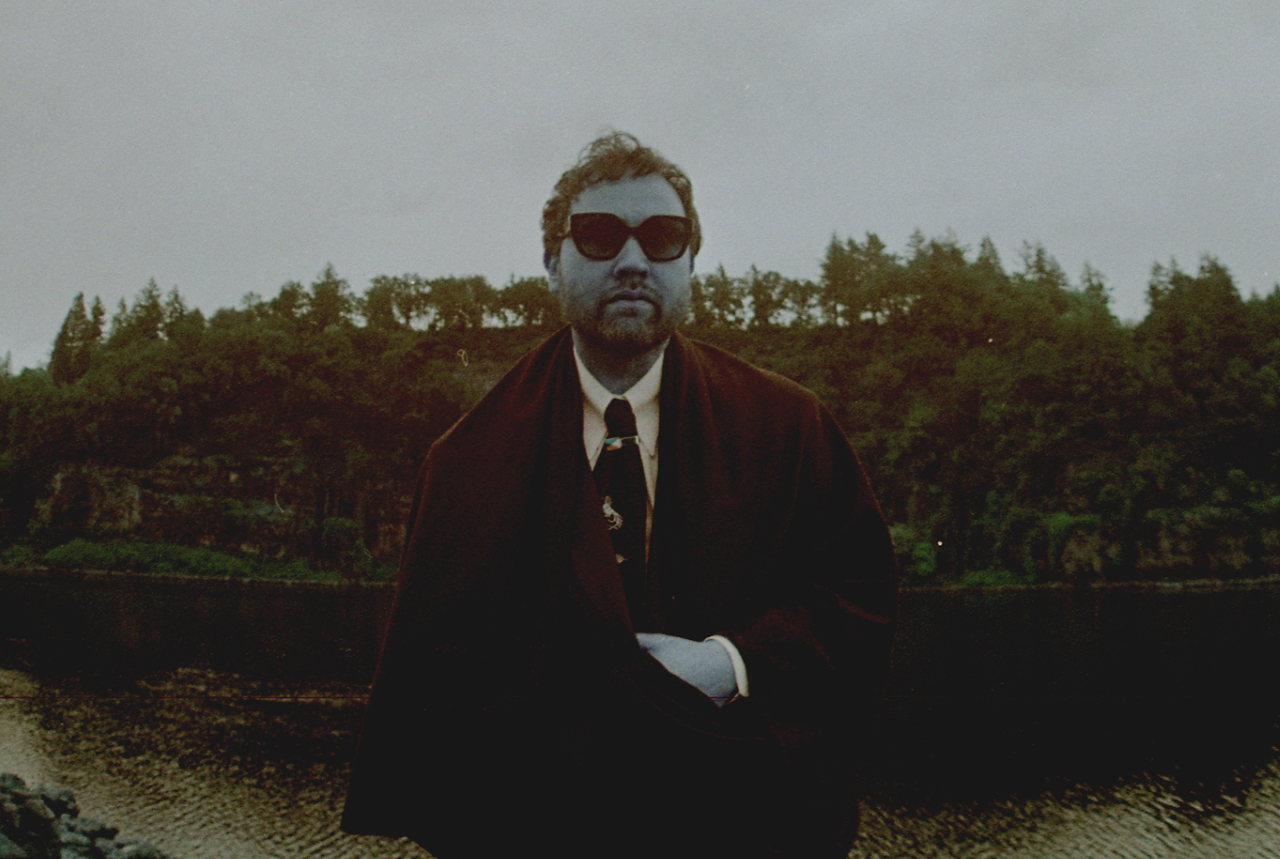 Artist Unknown Mortal Orchestra standing in front of a lake