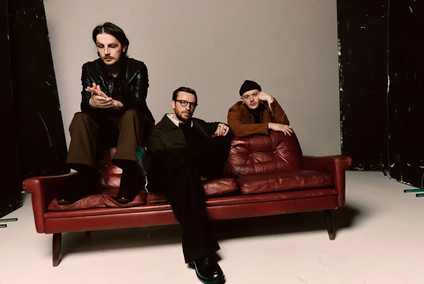 Three men on a red leather coach