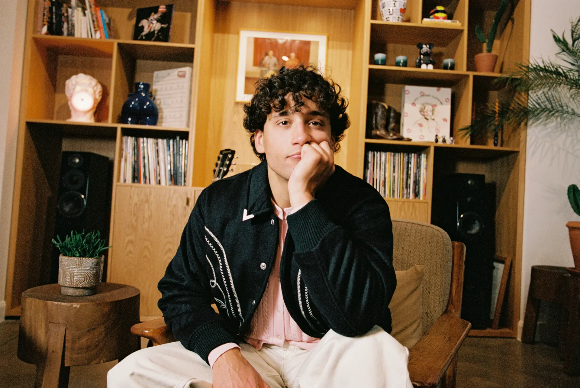 khakikid sitting down in front of a book shelf