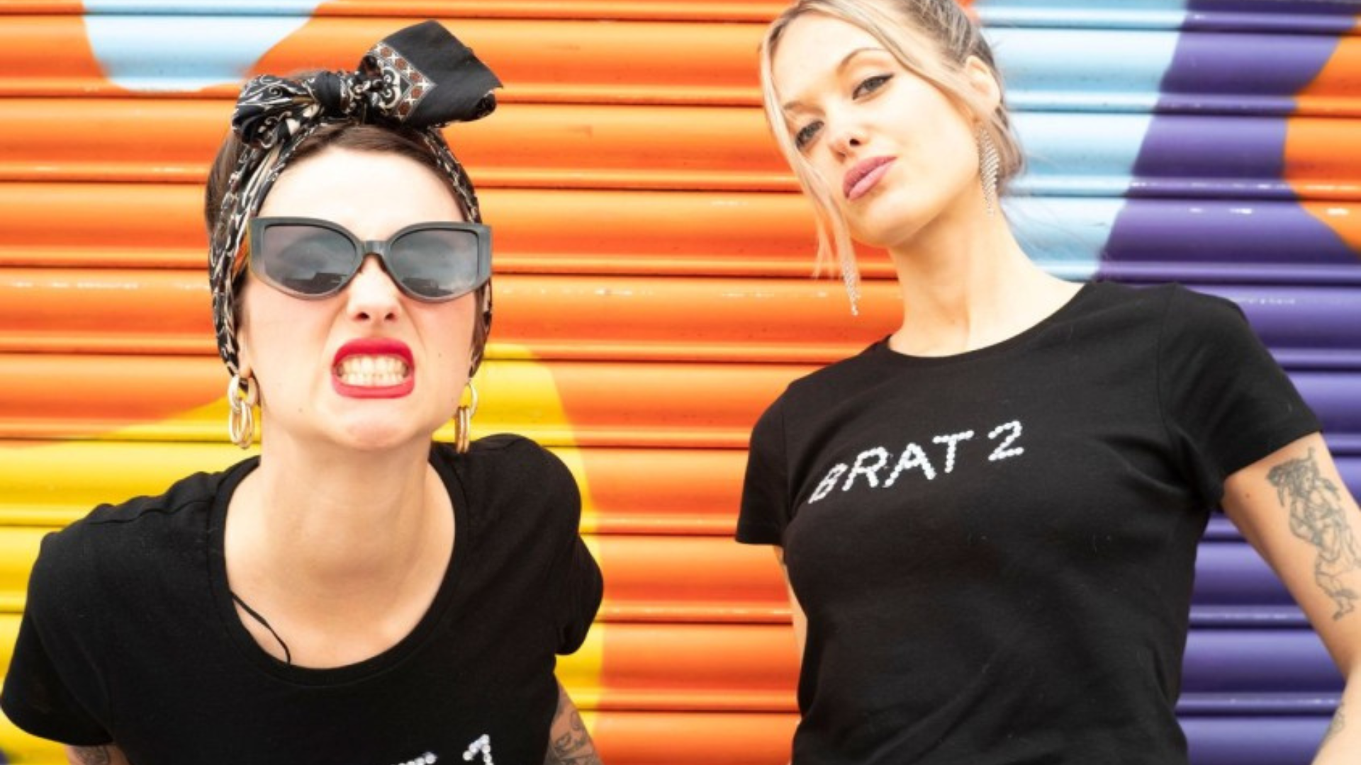 Promotional picture of Bratakus, 2 females looking into the camera with a coloured background.