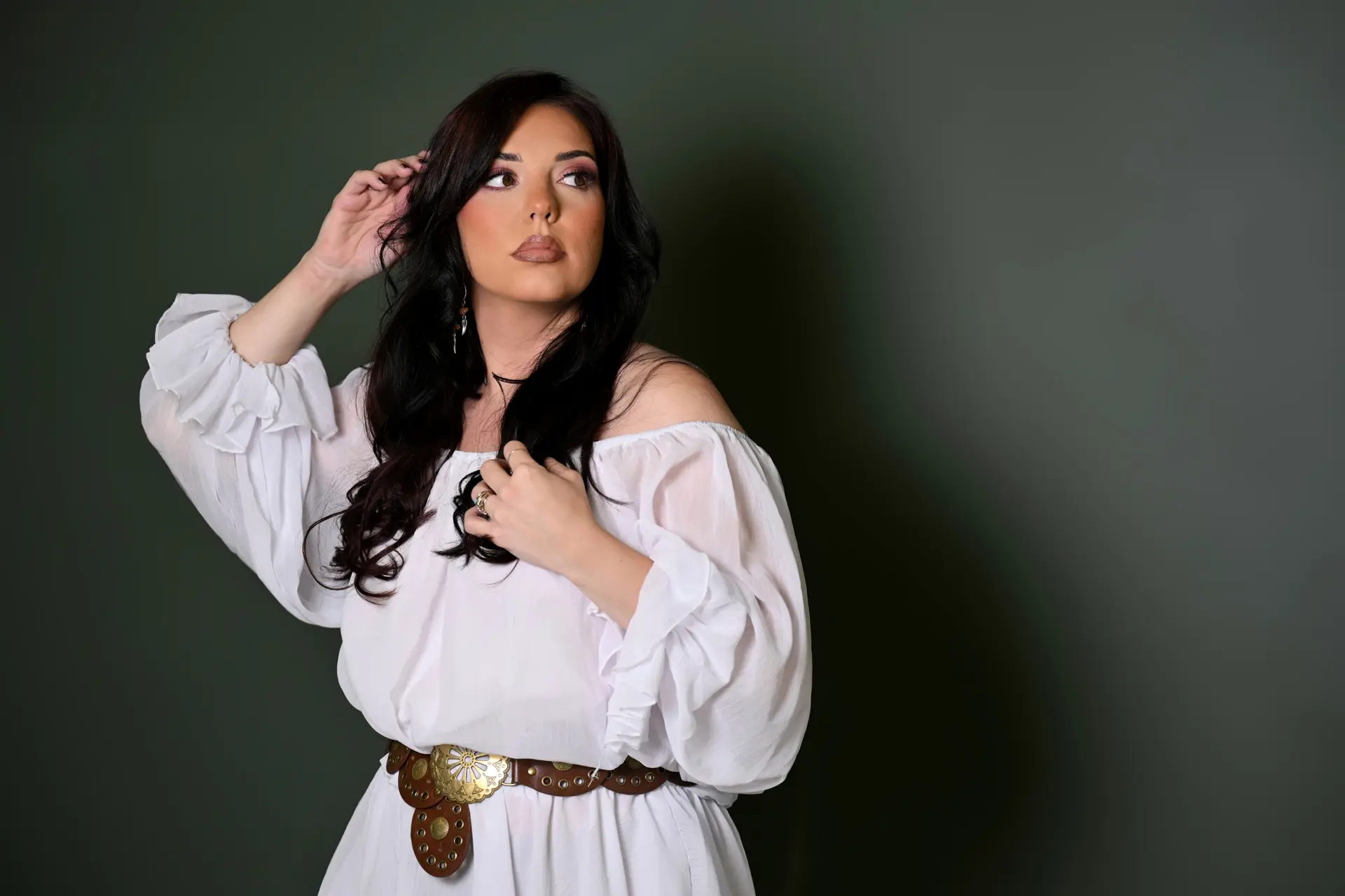 Woman posing in white dress against a black background