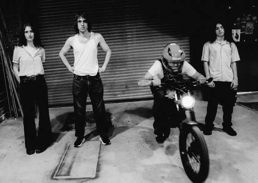 Four people in a garage one on a motorbike