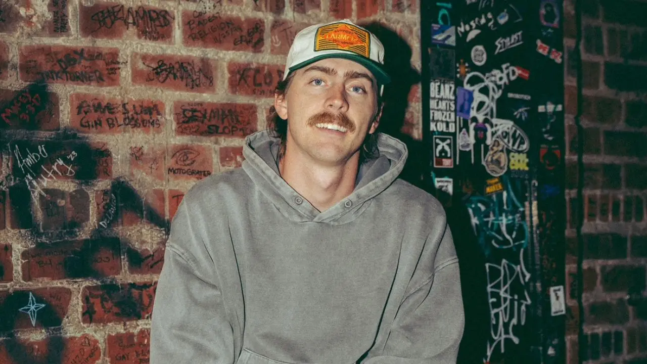 Artist Dylan Gossett sitting in front of a brick wall