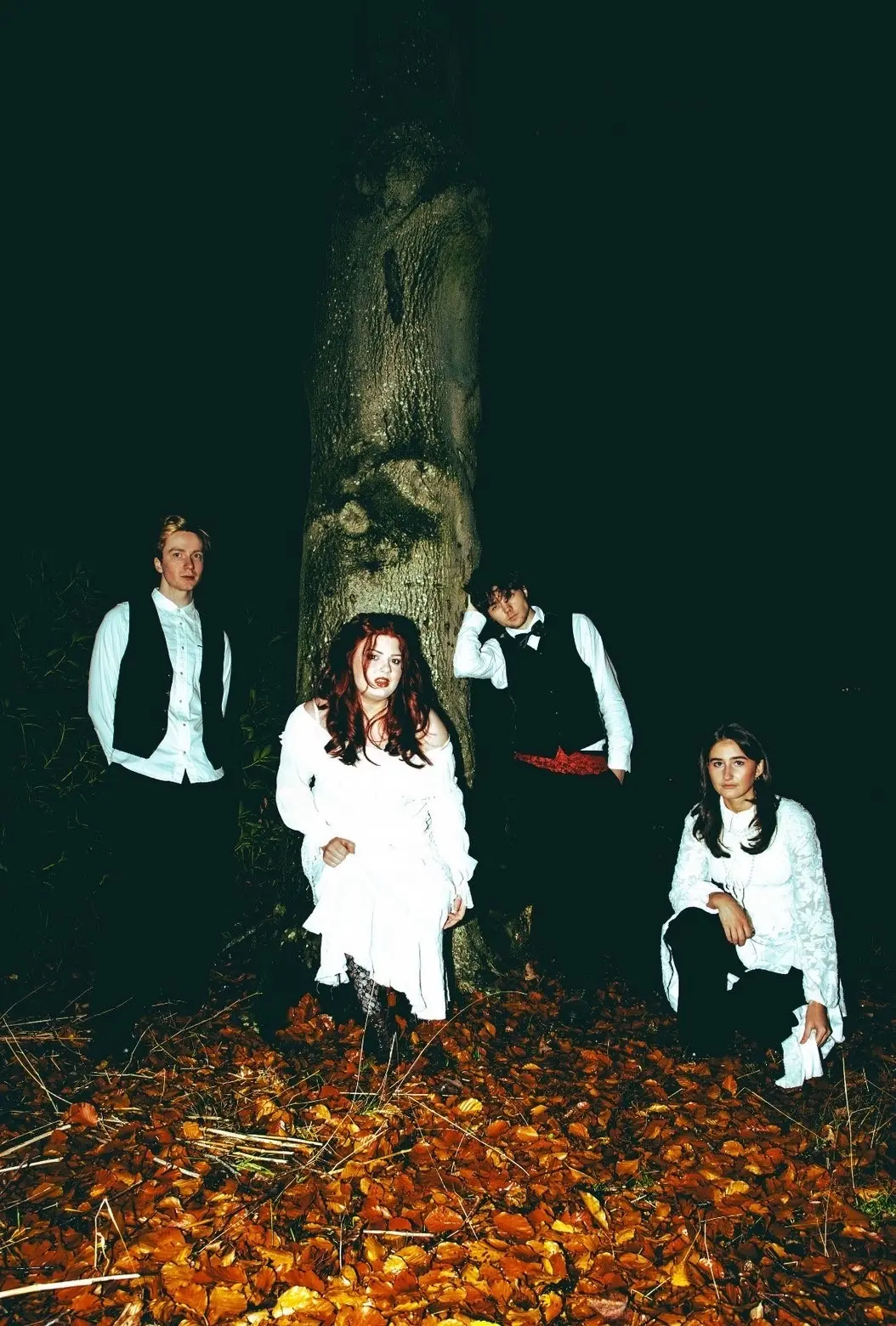 band of 4 members posing in the woods at night